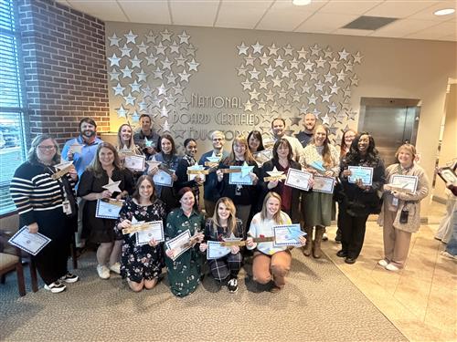  group pic of two dozen madison city school teachers with the honor wall in background of stars